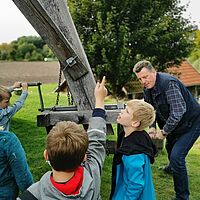 Kinder versuchen mit dem Müller die Mühle auszurichten