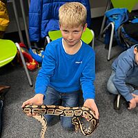 Junge hält Schlange auf seinen Händen.