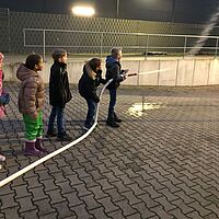 Kinder erfahren am Wasserschlauch der Feuerwehr wie viel Kraft Wasser hat.